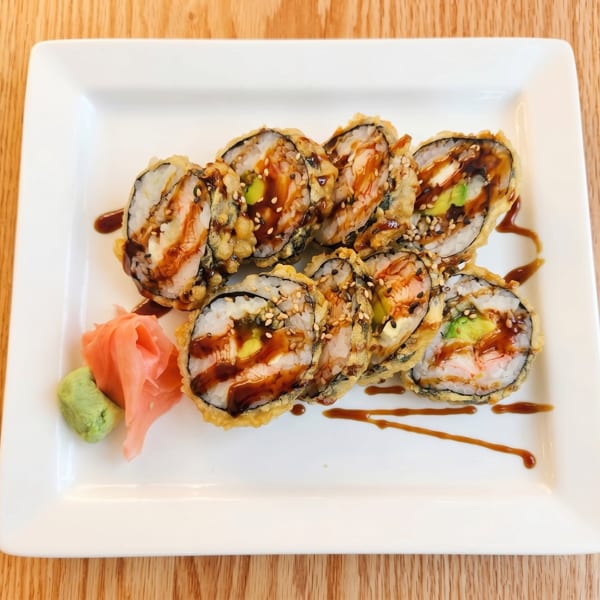 Tempura-fried sushi rolls with eel sauce, sesame seeds, avocado, and shrimp, served with ginger and wasabi.